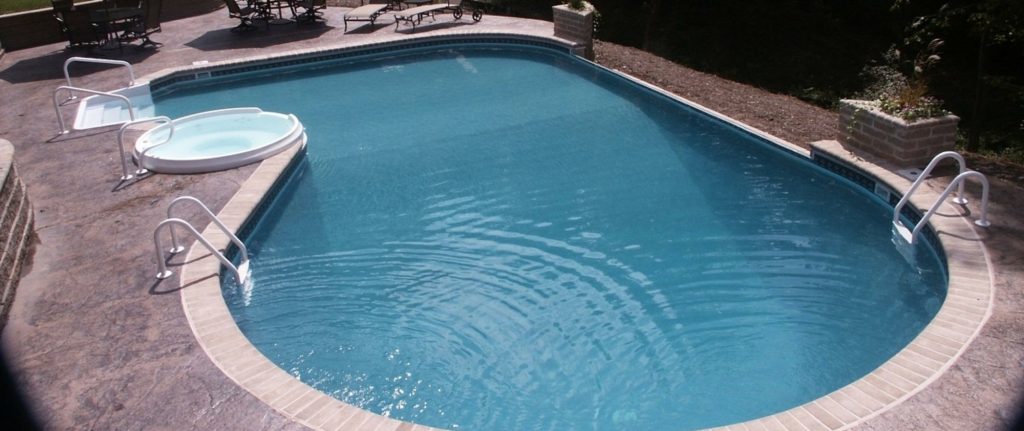 Freeform inground pool with stamped concrete decking in Winchester VA