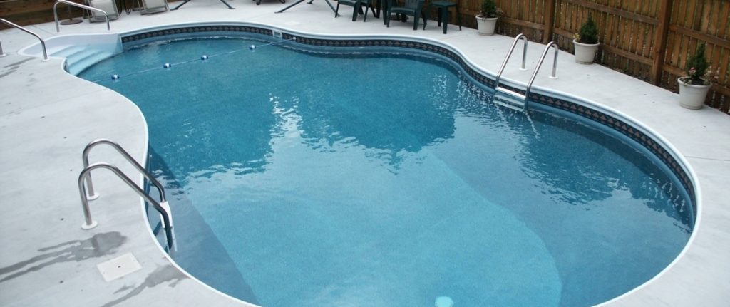 Freeform vinyl liner inground pool with concrete deck in Virginia