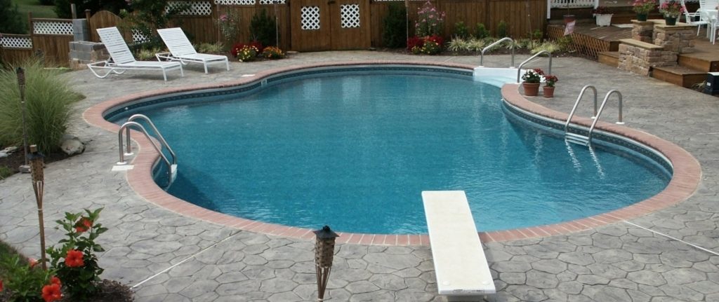 Kidney shaped inground pool with paver deck and diving board in Stephenson VA